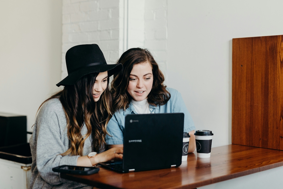 Two women drinking coffee and using a laptop
